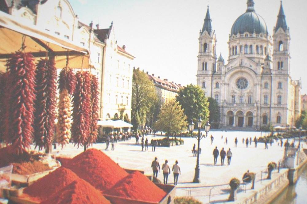 A market stall heaped with bright red ground paprika and strings of dried peppers