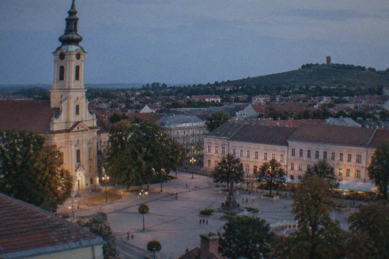A small Serbian town with a hilltop tower rising above red rooftops
