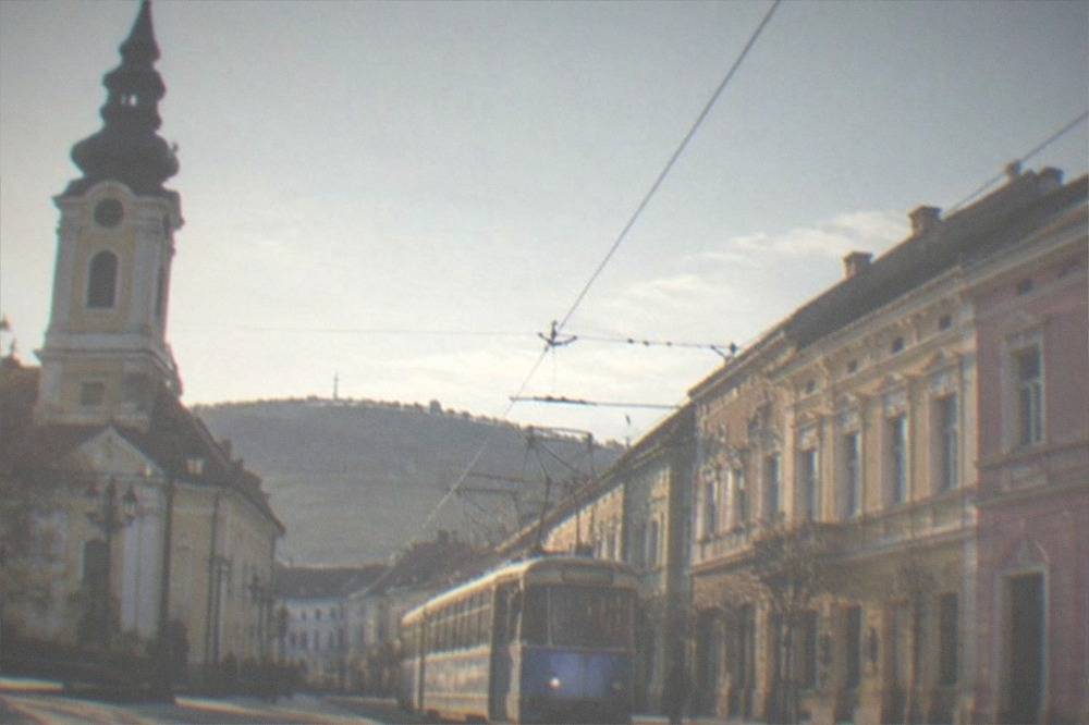 A tram moving along a street lined with colorful buildings