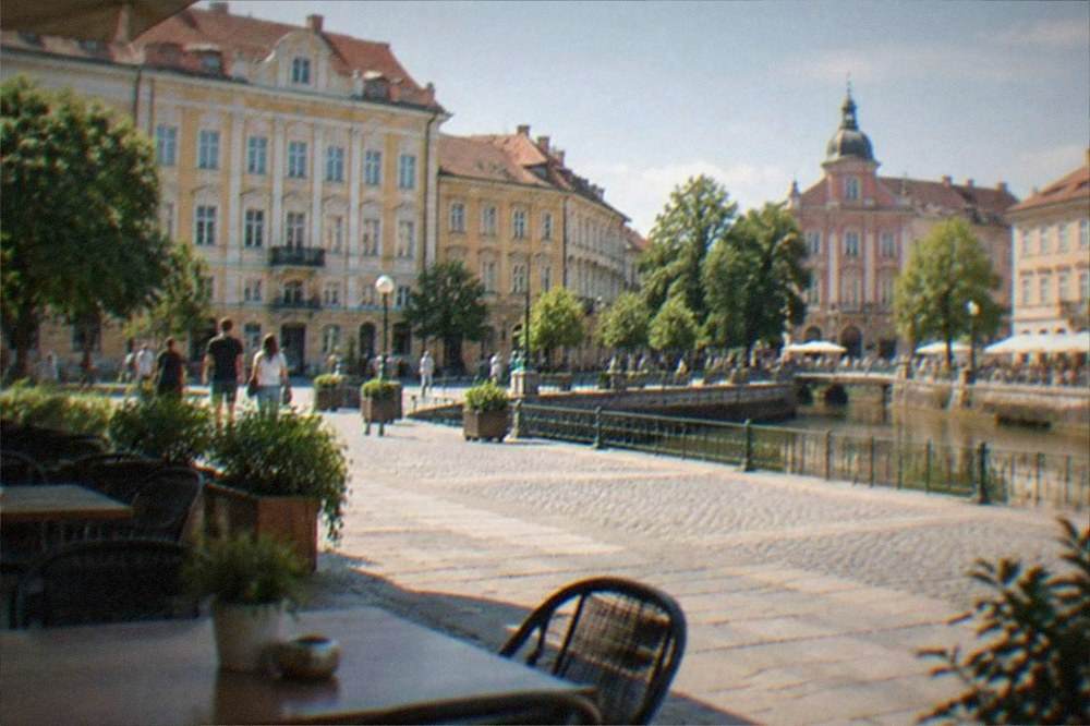 Outdoor cafe tables on a sunny square in Timisoara with people strolling