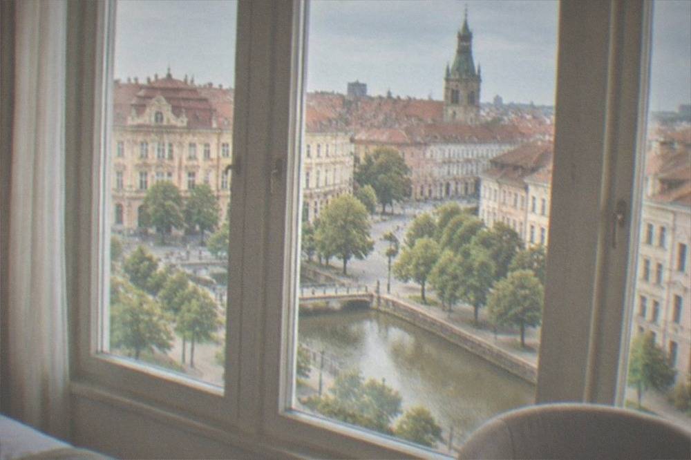 A cozy hotel room with tall windows and a view over rooftops in Timisoara