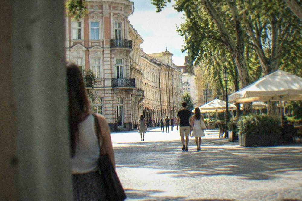 Sunlit street in the Cetate old town with pedestrians in light clothing