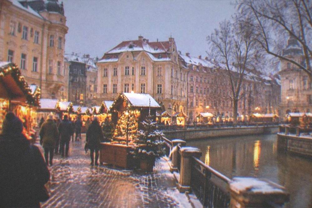 Illuminated Christmas market stalls in a Timisoara square at night with light snow
