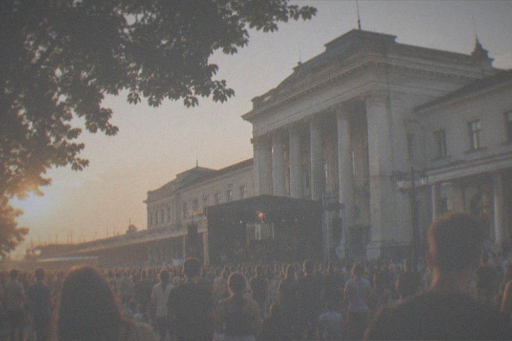An outdoor concert crowd in a city square on a summer evening