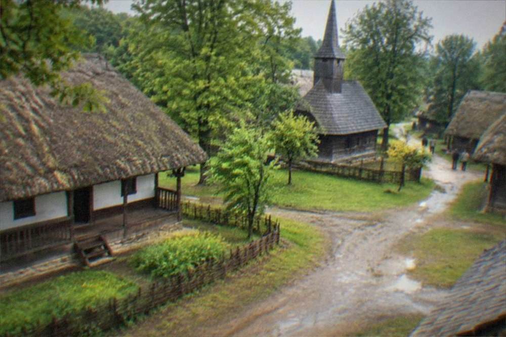 A traditional wooden church and farm buildings at an open-air village museum
