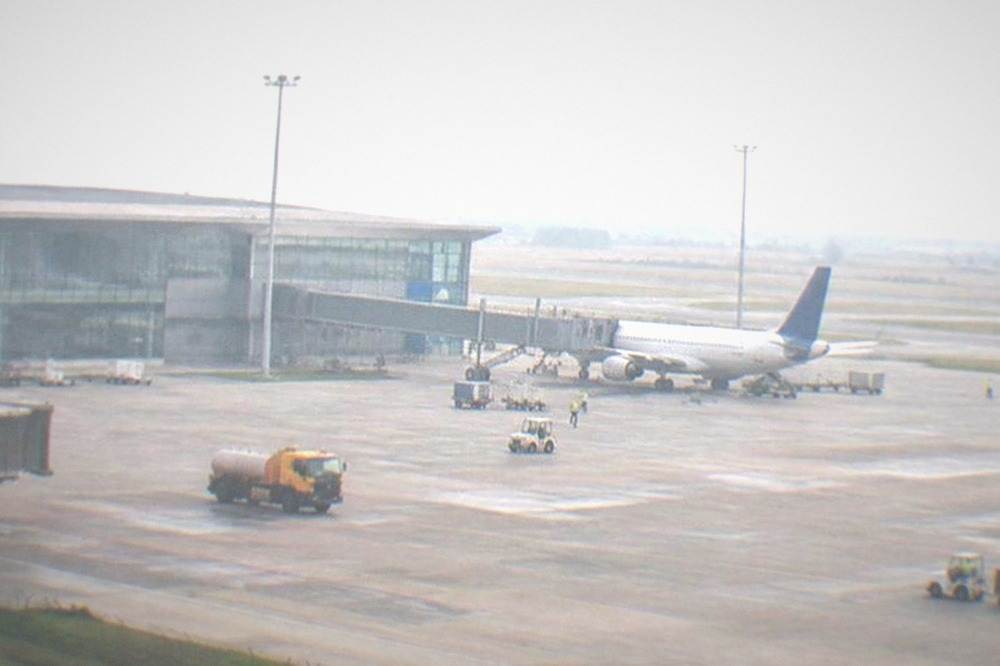 Maintenance vehicles and workers on an airport runway under an overcast sky