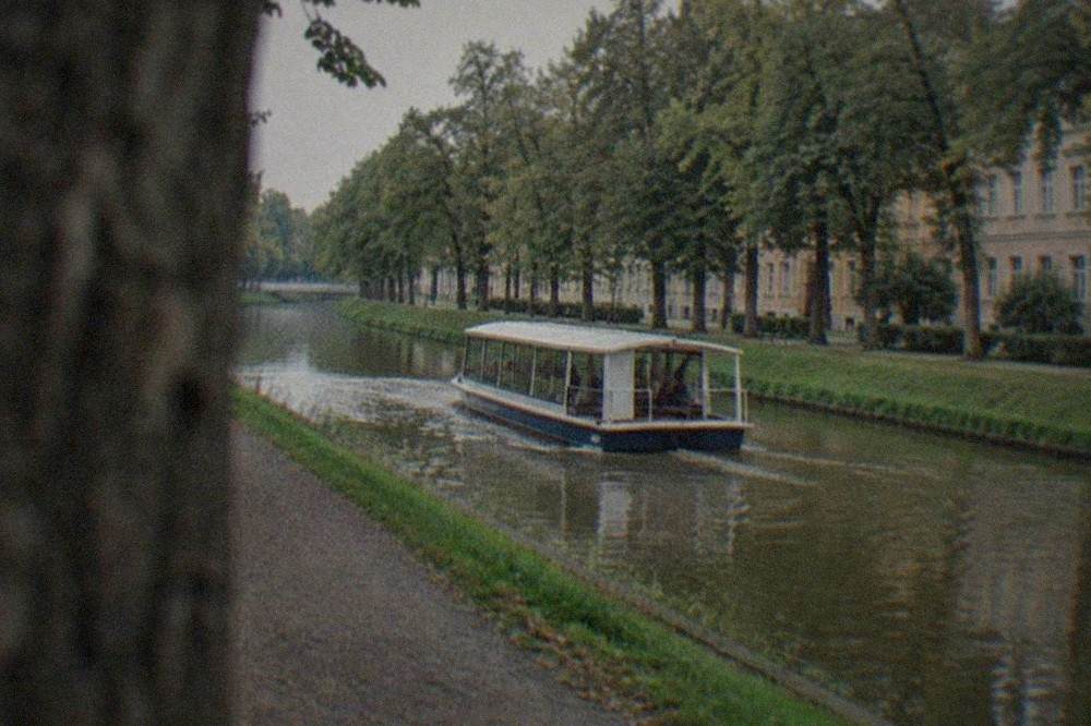 A small passenger water bus traveling along the Bega canal between green banks
