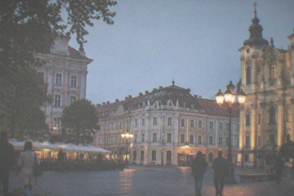 Pedestrians crossing a baroque square in Timisoara's old town