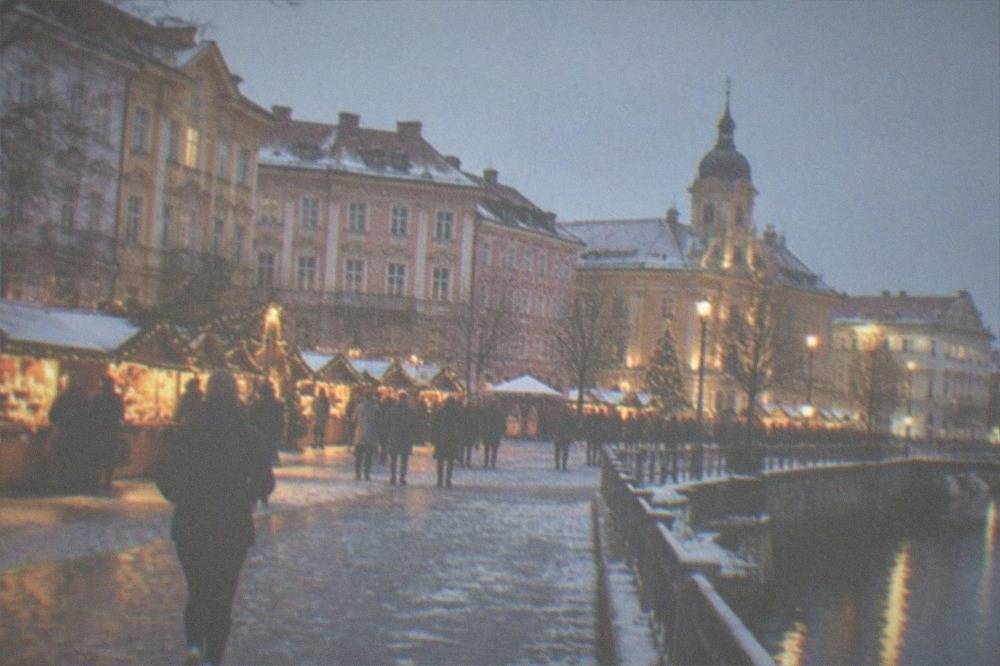 A snow-dusted square in Timisoara with a lit Christmas market in the evening