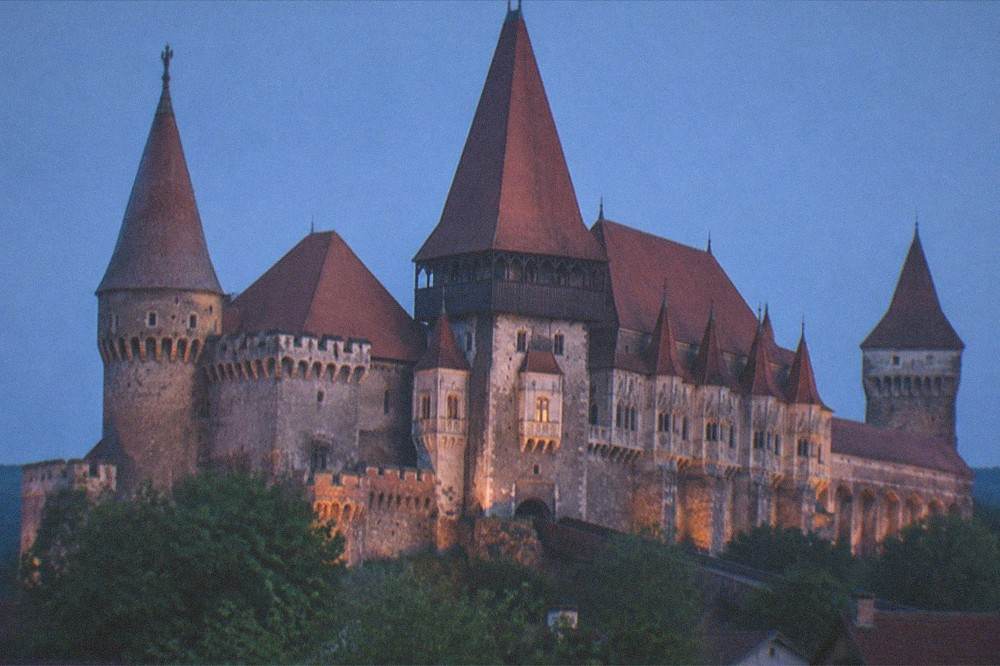 A Gothic castle rising above a town in Transylvania under a clear sky