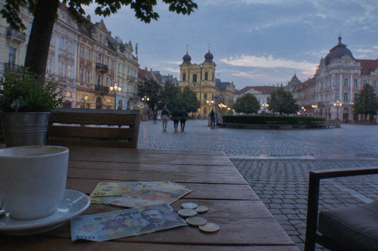 Romanian leu banknotes and coins arranged on a wooden cafe table in a Timisoara old town square