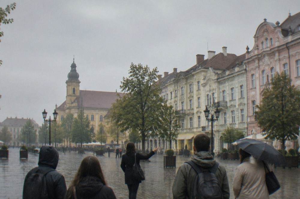 A local guide speaking to a small group of visitors on a street in the Timisoara old town