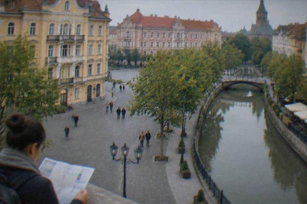 A visitor reading a bilingual street sign on a building facade in Timisoara