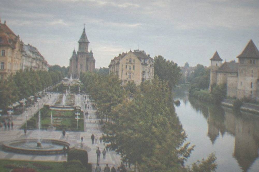A medieval stone castle with towers reflected beside a river