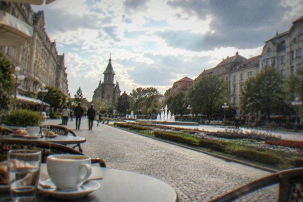 Outdoor cafe tables on a cobblestone street with coffee cups and pastries