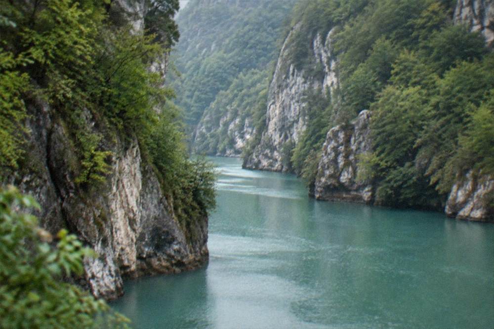 Turquoise river water winding through a forested limestone gorge in the Banat mountains