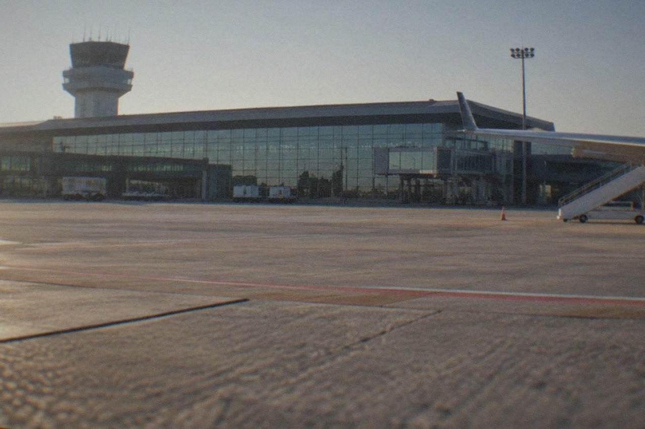 A modern airport terminal building with glass facade under a clear sky