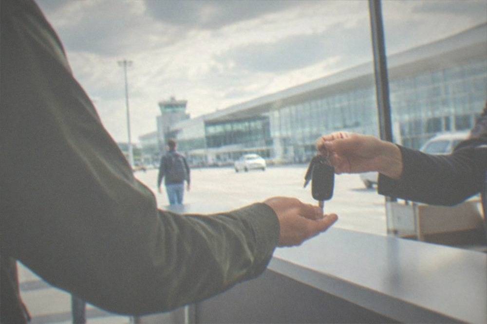 A rental car being handed keys at an airport counter