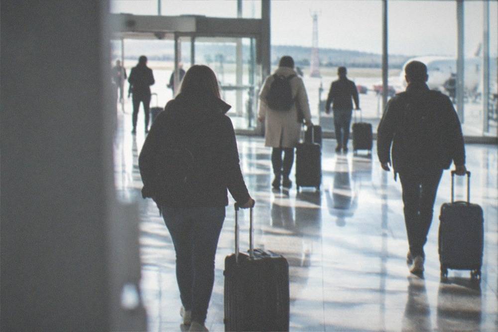 Travelers with suitcases walking through a bright airport arrivals hall