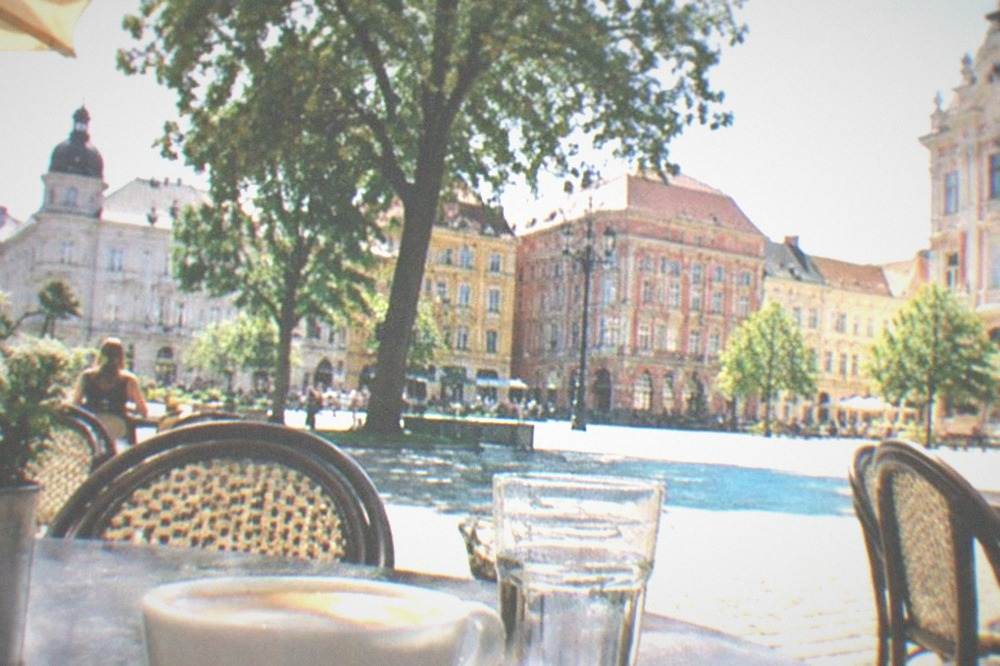 A cafe terrace in a European old town square with coffee cups on tables
