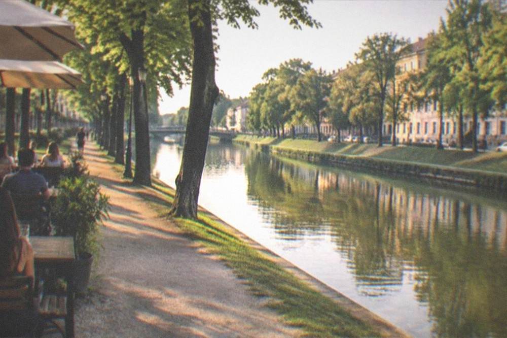 People enjoying drinks at an outdoor terrace beside the Bega canal in the evening