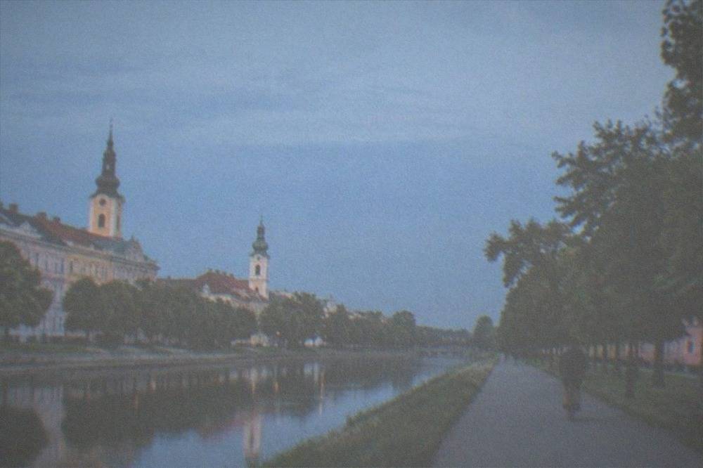 A cyclist crossing a cobblestone square lined with colorful baroque buildings and church towers