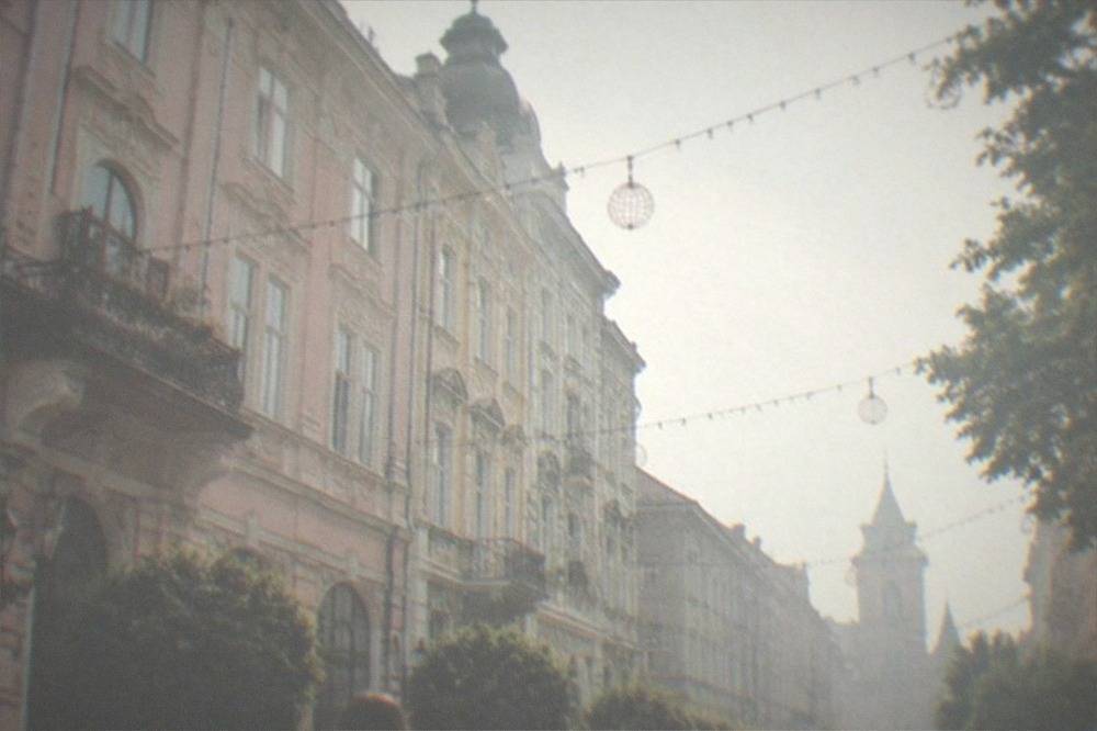 People walking through a decorated old town street with festive lights strung overhead