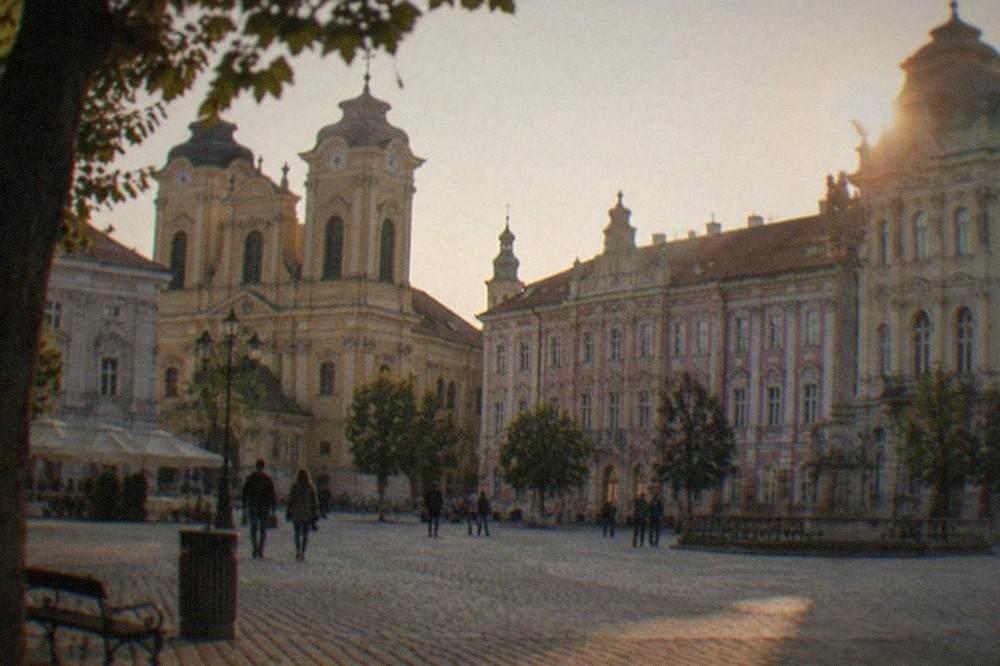 Baroque facades and church towers around a cobblestone square in the Cetate old town