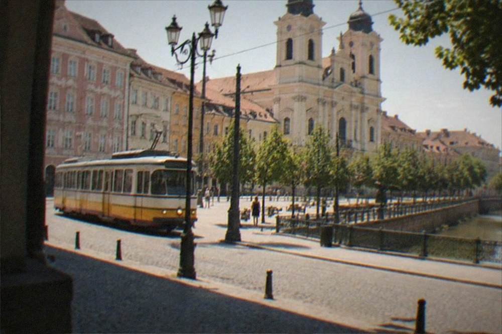 A vintage-modern tram passing a historic church facade on a Timisoara boulevard