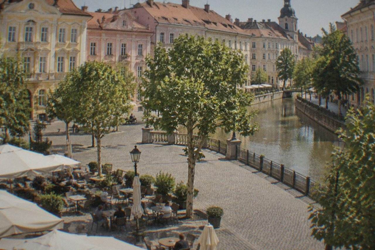 Outdoor cafe tables on a cobblestone square in Timisoara with pastel baroque buildings behind them