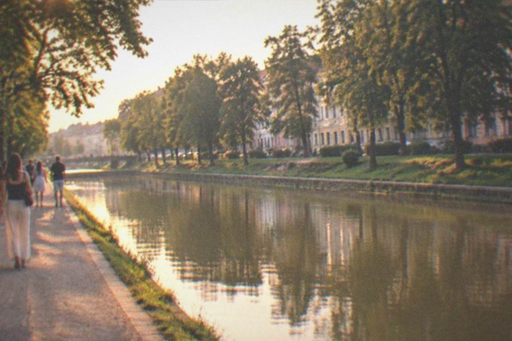 People strolling along the Bega canal promenade in Timisoara at golden hour