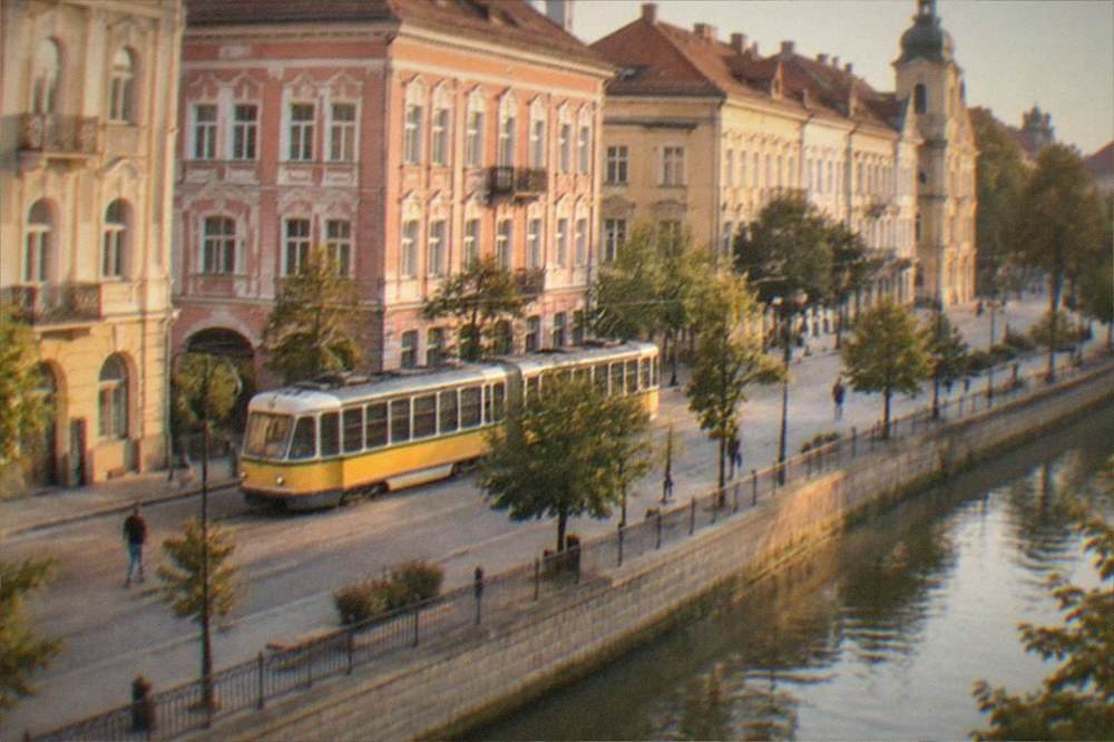 A tram passing colorful historic buildings on a street in Timisoara