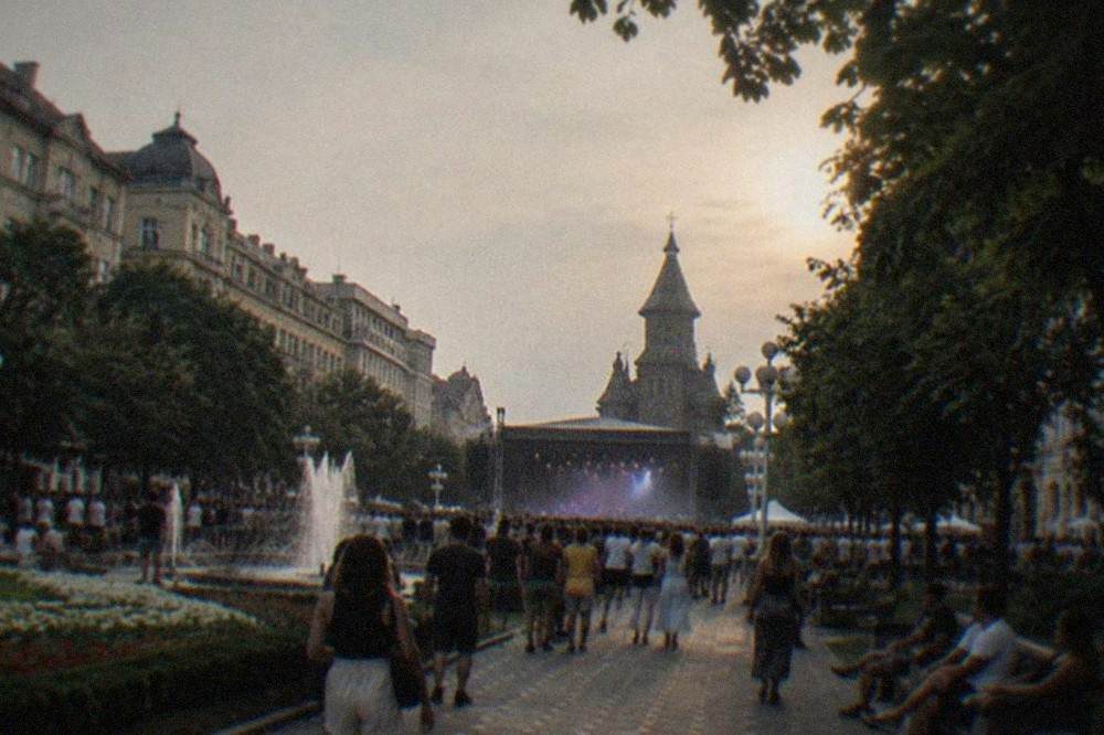 Open-air music stage at a summer festival with crowds and evening light