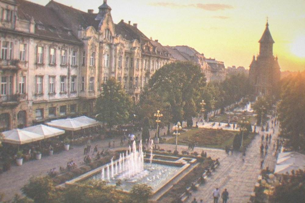Elegant city square lined with ornate buildings and outdoor cafe tables