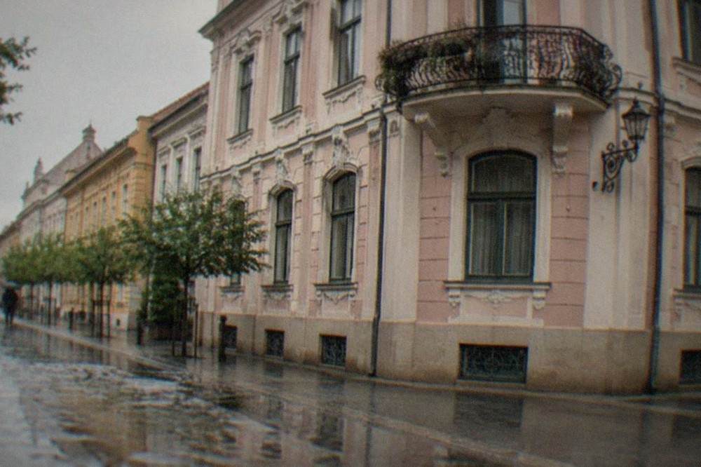 A pastel-colored Secession-style villa facade in a quiet Timisoara side street with wrought iron details