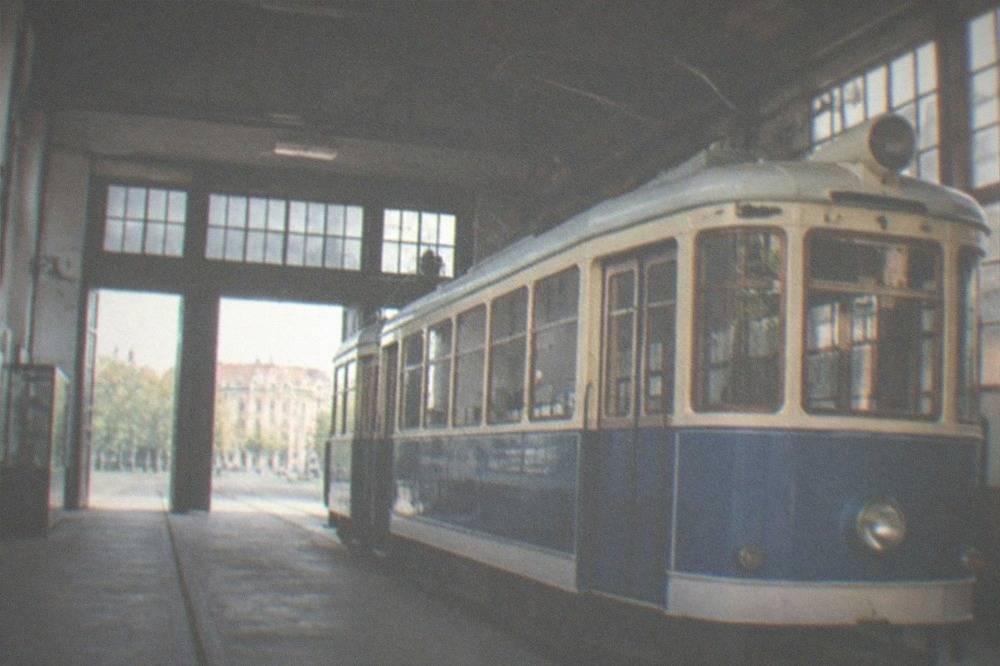 A vintage blue and cream tram parked inside a museum shed in Timisoara