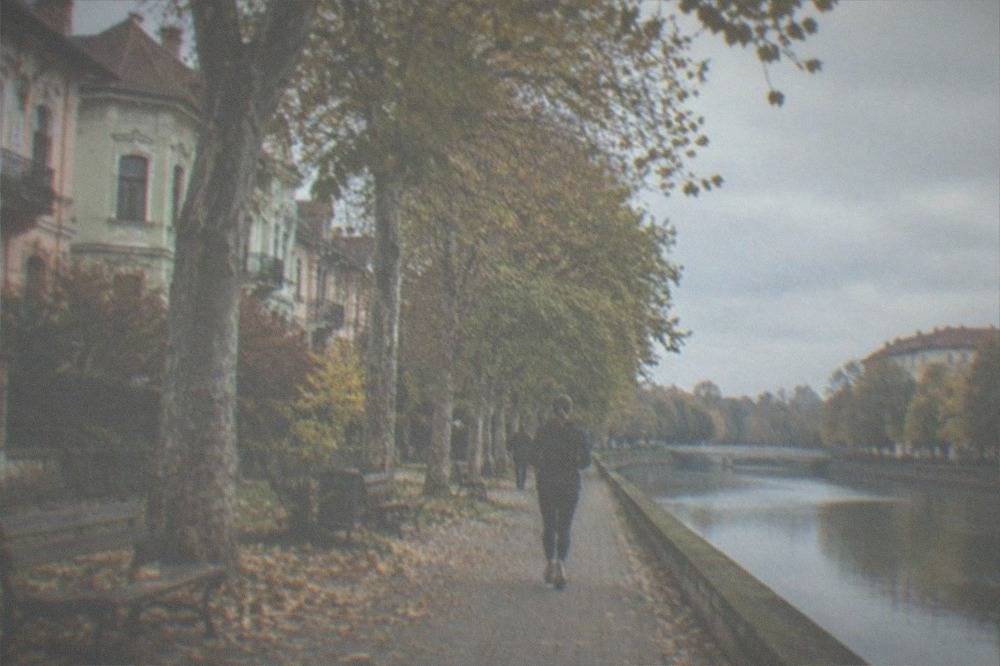 Empty park benches and autumn trees along a canal promenade in a Romanian city