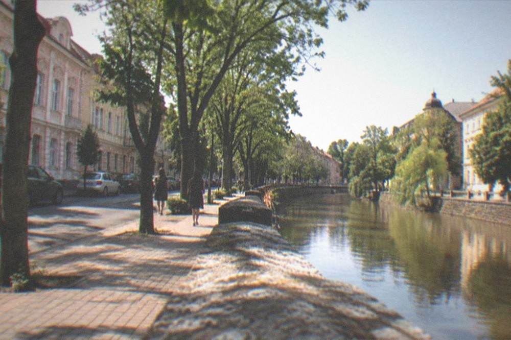 A backpacker with a map looking out over a river running through a European city