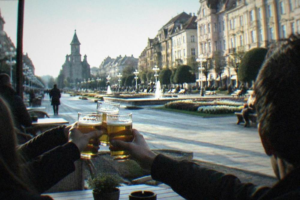 Friends toasting with beer glasses on a pub terrace in the evening