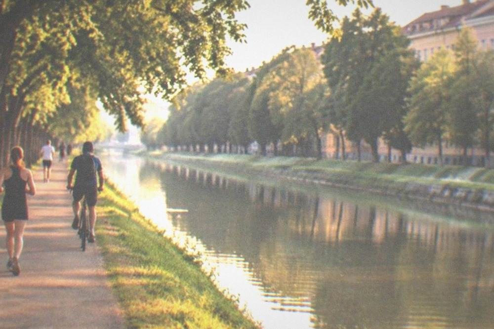 Runners and cyclists on a paved path beside the Bega canal in Timisoara