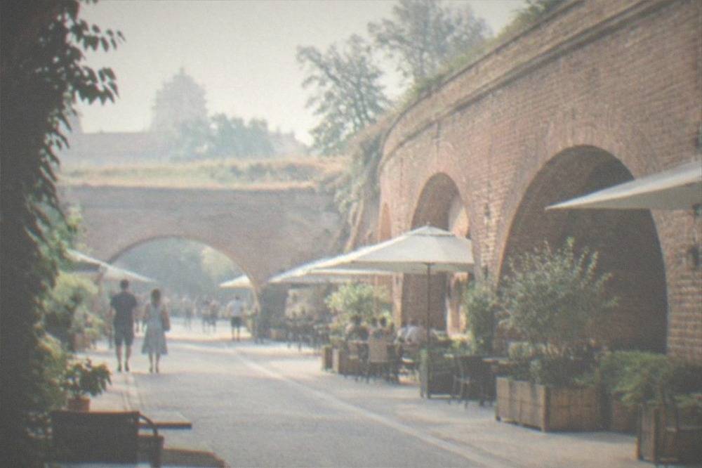Curved brick walls of a restored bastion forming an arch over a walkway with cafes