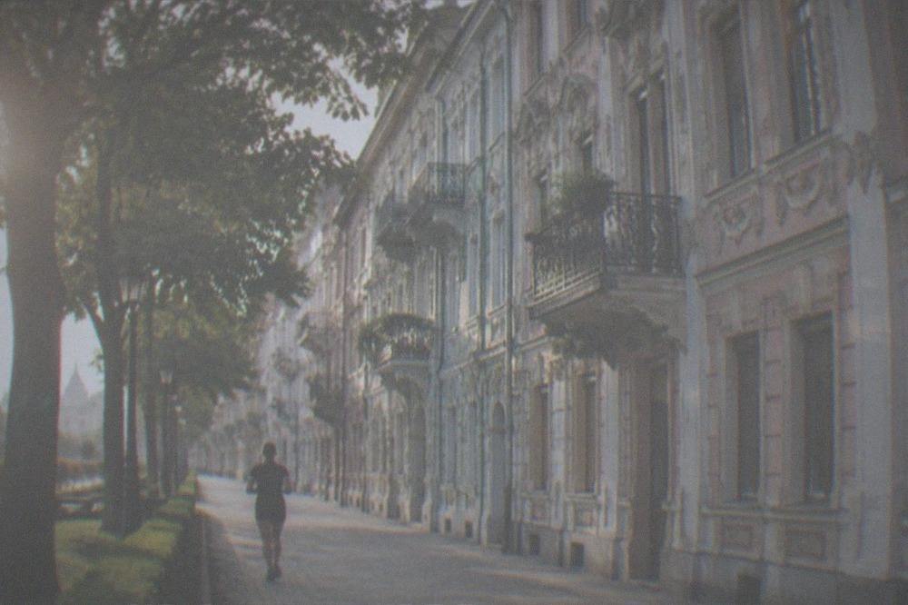 Faded pastel apartment facades with tall windows on a quiet tree-lined street