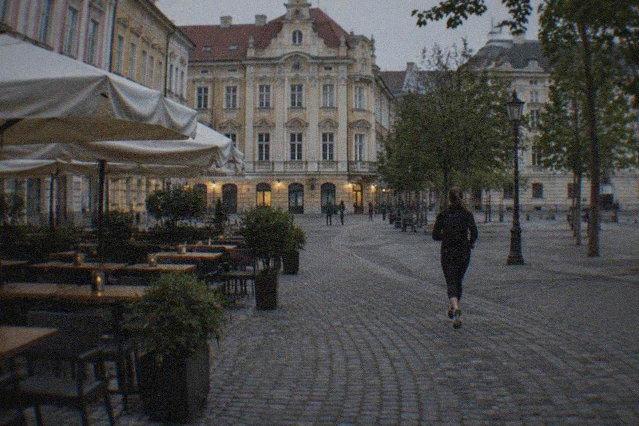 Outdoor tables on a cobbled square in Timisoara's old town at dusk