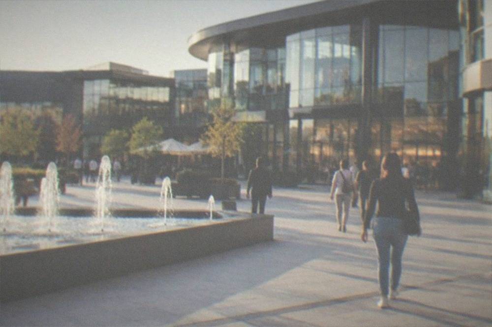 A modern shopping mall interior with a wide walkway, storefronts and shoppers in Timisoara