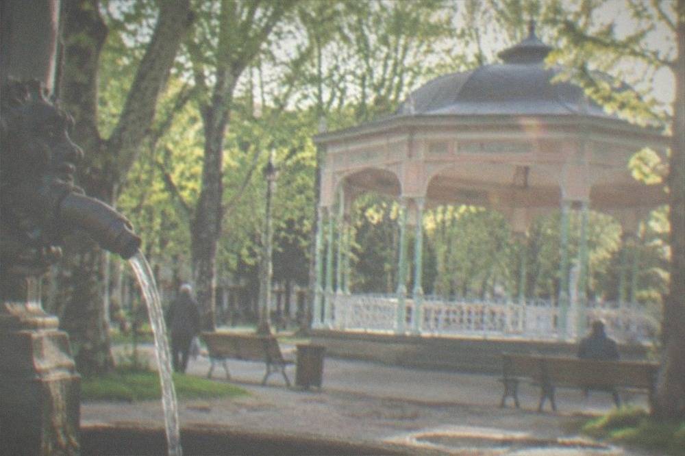 Mineral water flowing from an ornate spring spout in a historic spa town park in the Banat