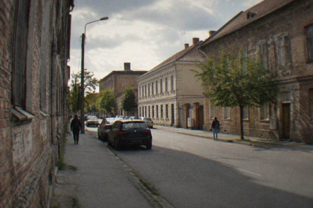 A painted mural covering the entire side wall of a residential building seen from a narrow street