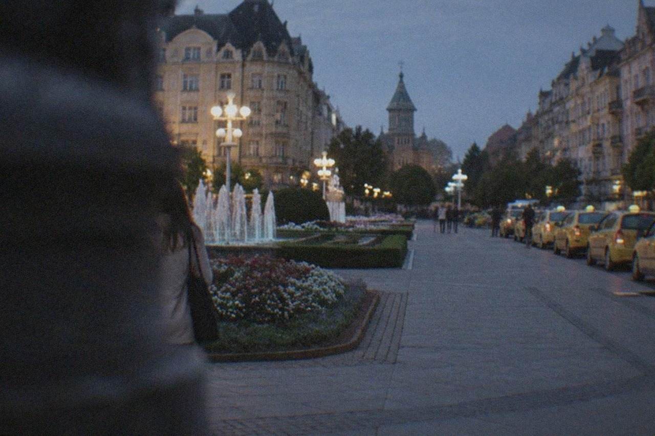 A row of taxis waiting at a rank on a European city square at dusk