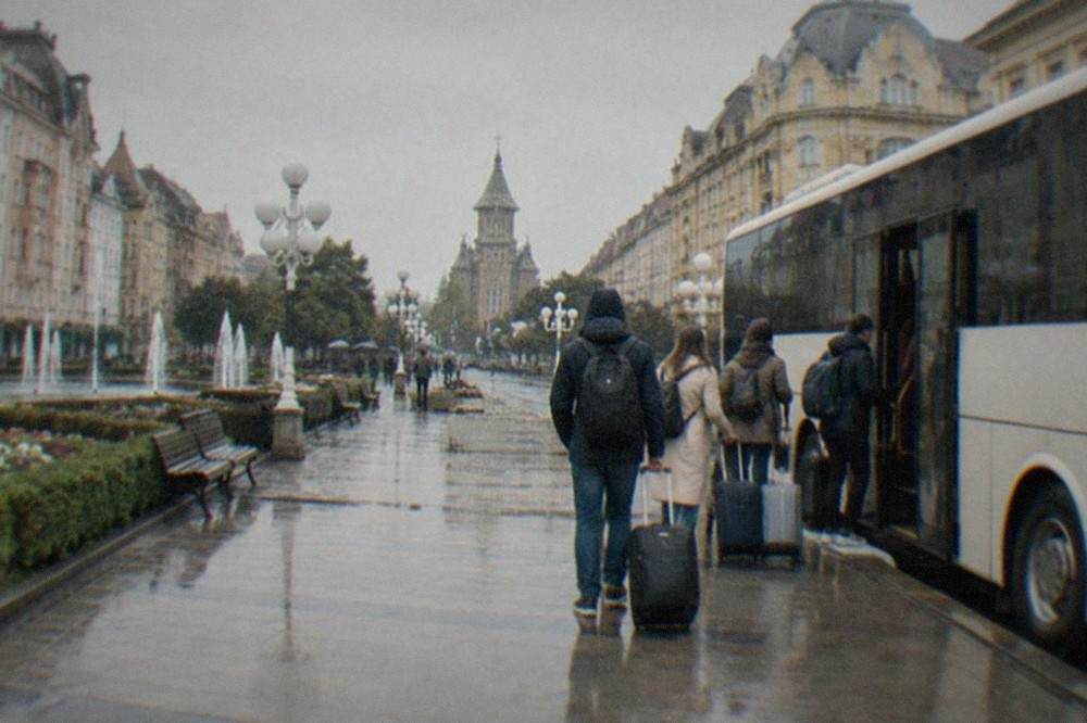 Passengers with luggage boarding an airport shuttle bus outside a small European terminal