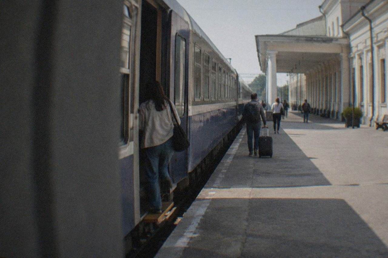 A direct train standing at a railway platform beside an open carriage door