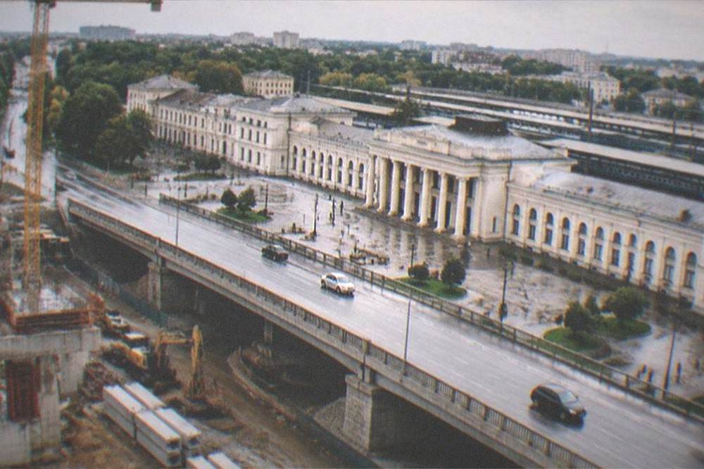 A construction site with cranes and concrete segments beside a road bridge